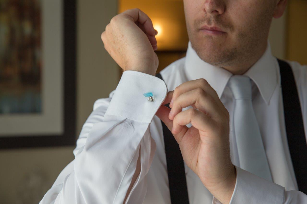 Groom puts on seglass cufflinks