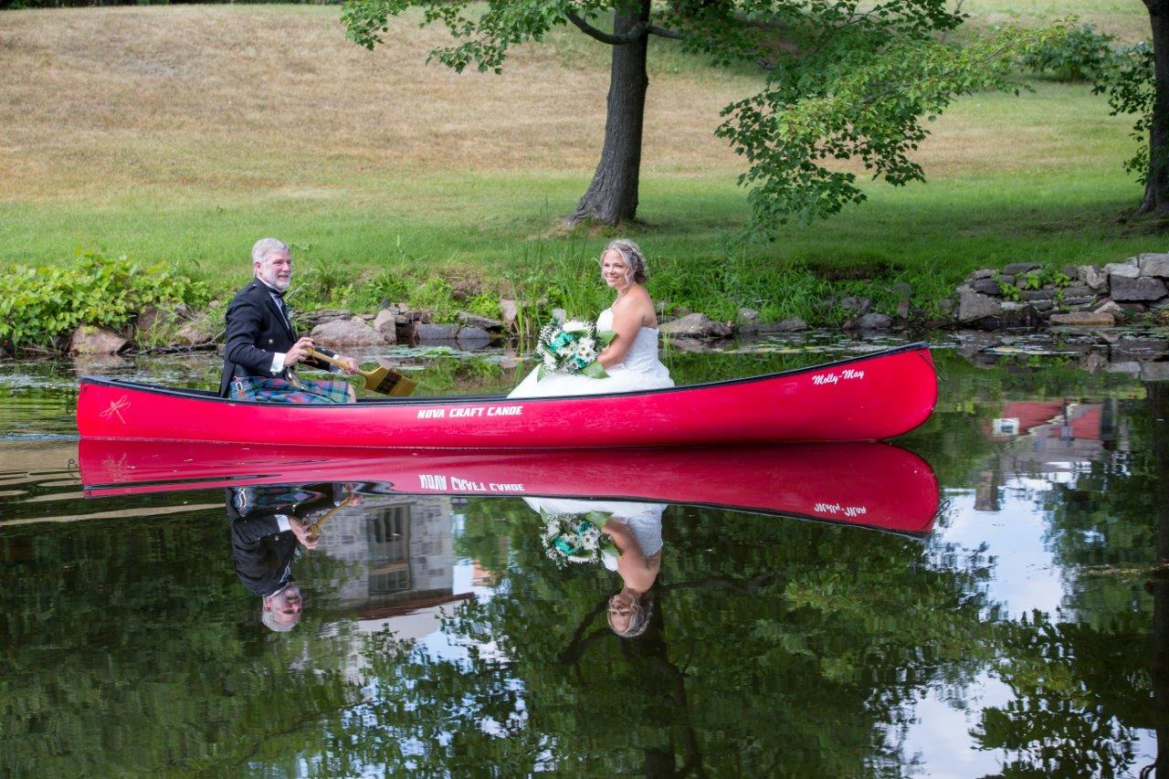 A father paddles his daughter, the bride, in a red canoe to her wedding