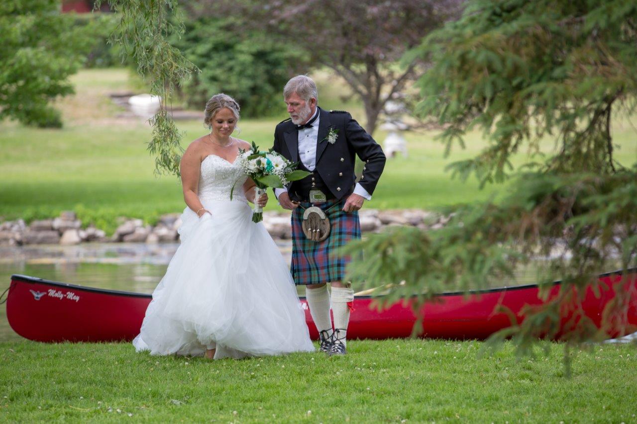 Father helps his daughter, the bride, out of a red canoe