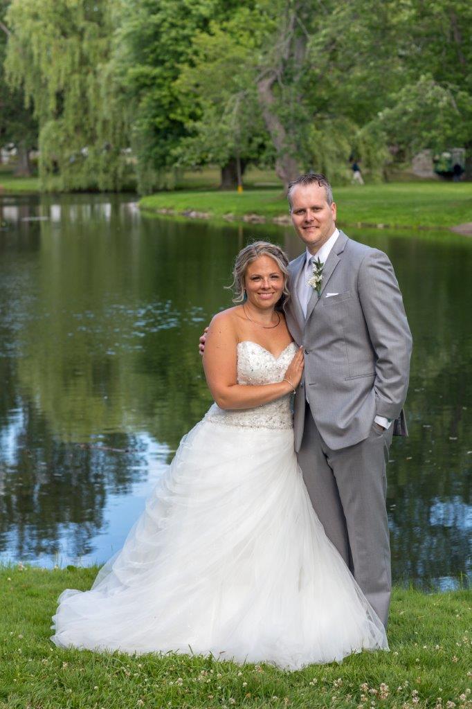 The bride and groom pose for a photgraph by the lake