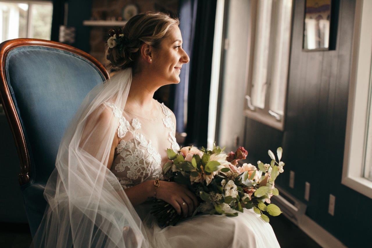 Bride holding a bouquet of flowers looking out the window