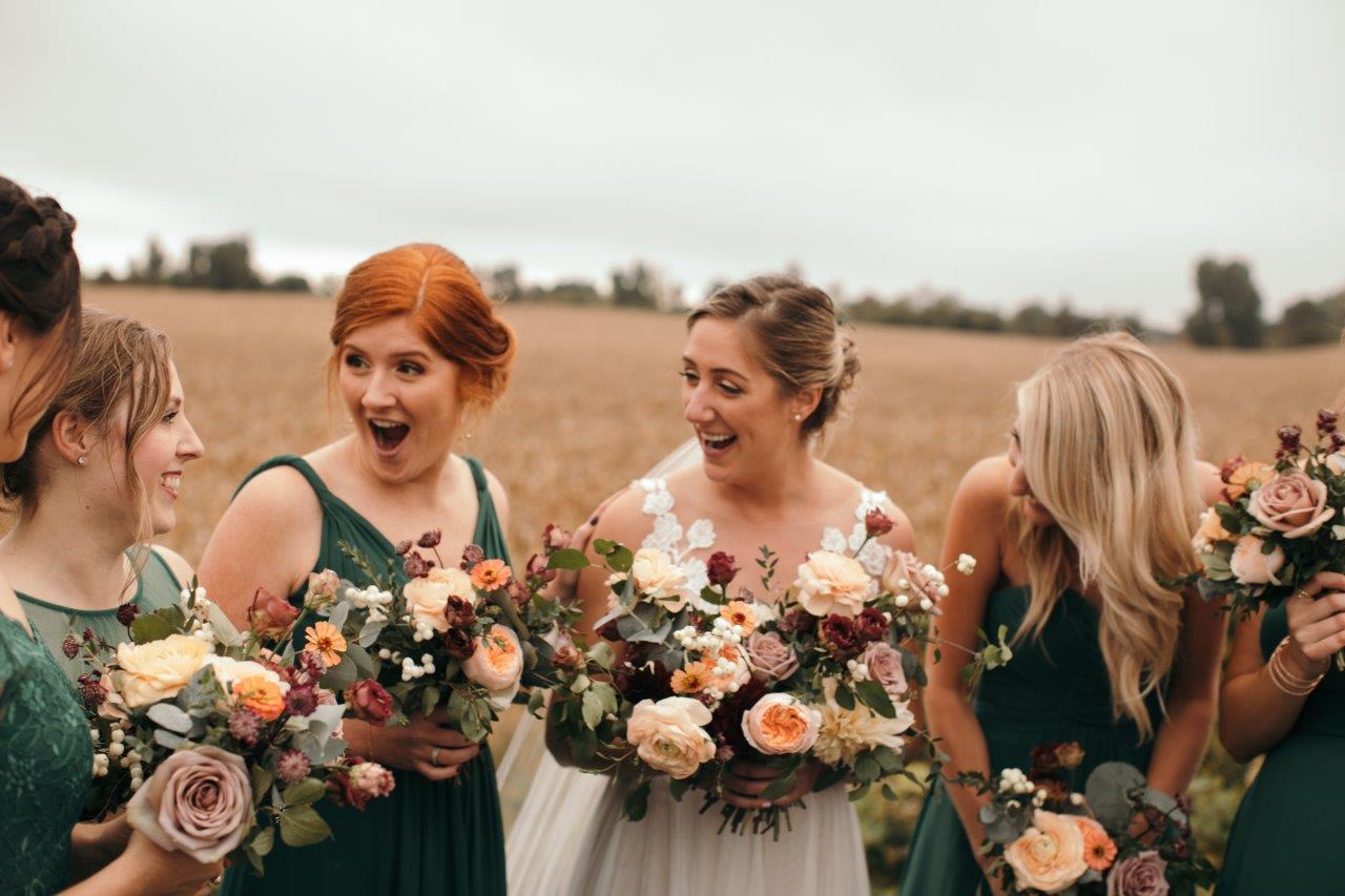 Bride talks with her bridesmaids in a wheat field